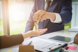– Agents are giving house keys of customer and holding dollar us bank at agency office. Agreement and real estate concept. @ itchaznong / Fotolia