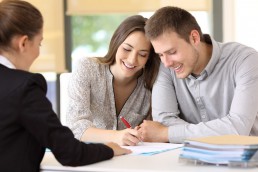 Happy couple signing a contract at office © Antonioguillem / Fotolia